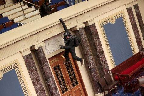 A protester is seen hanging from the balcony in the Senate Chamber on January 06, 2021