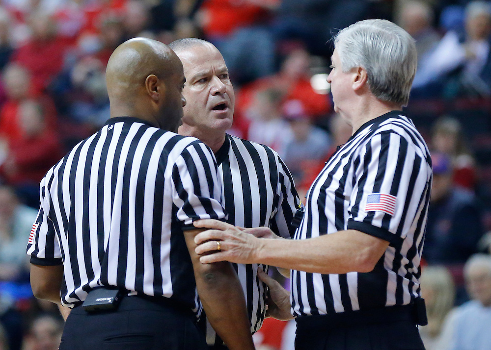 Three+basketball+officials+discussing+a+call.