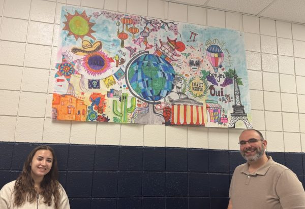 Senior Bella Minyo and Japanese teacher Mr. Steve Balsomico with the banner created at Around the World event. 